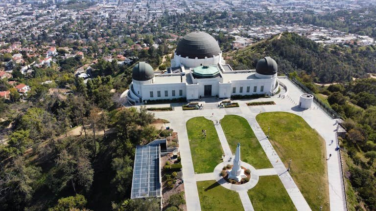 A stunning aerial shot of Griffith Observatory overlooking Los Angeles cityscape and greenery.