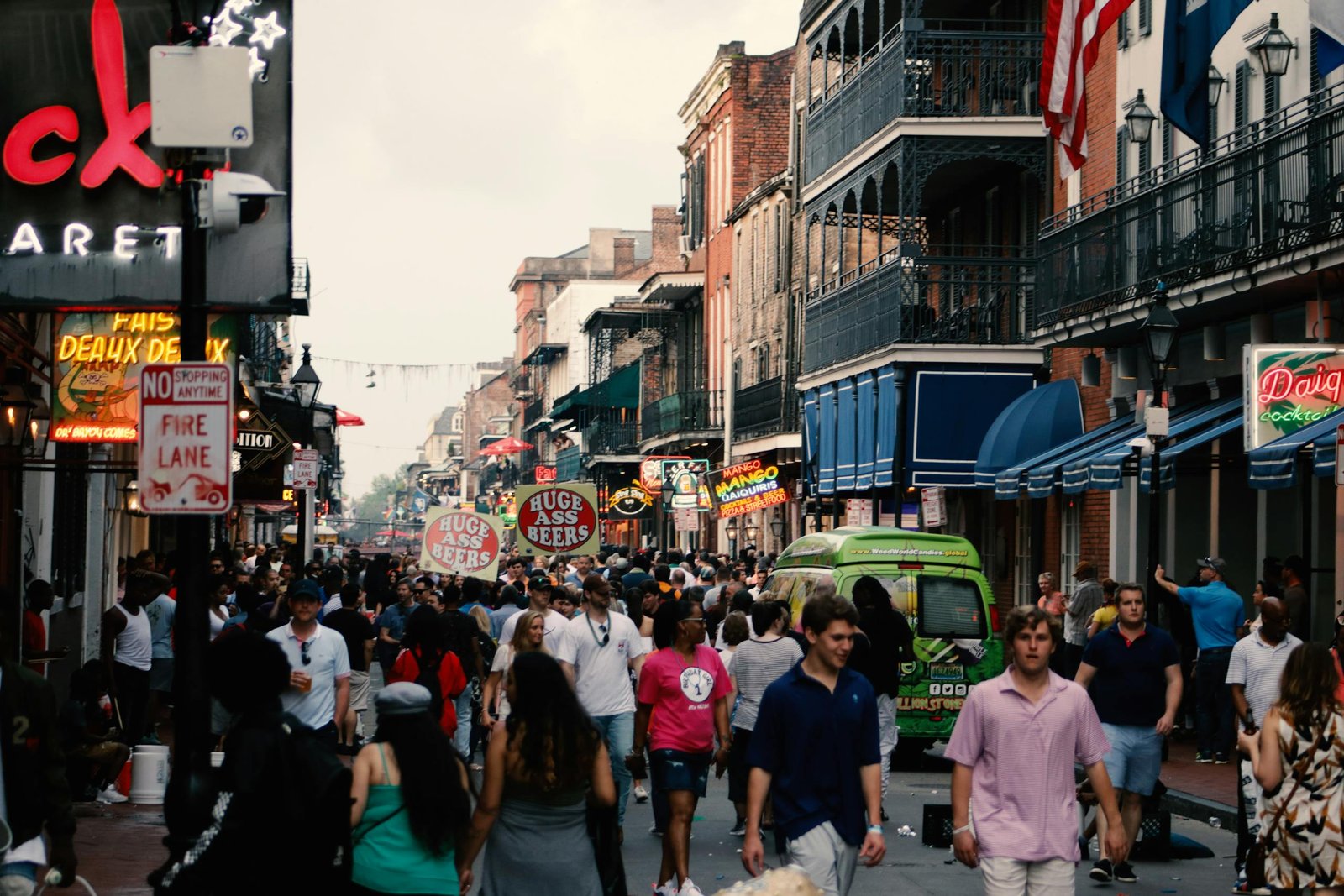 Bustling street scene in the New Orleans French Quarter filled with tourists and local shops.