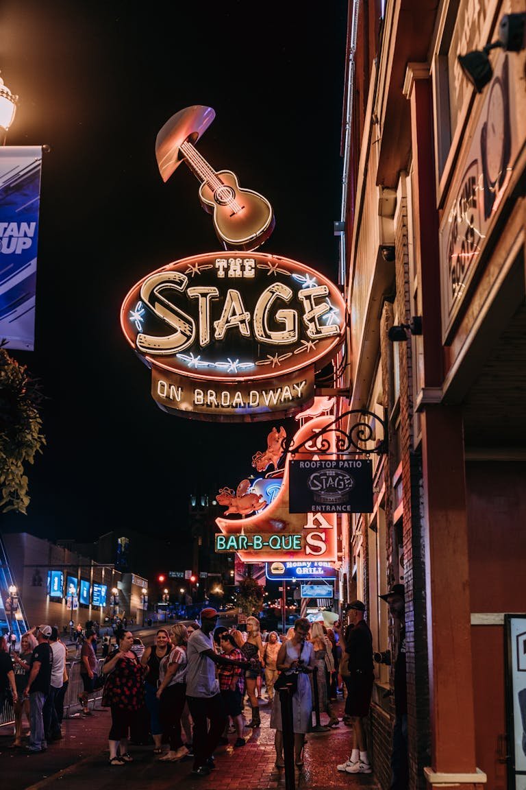 Dynamic nightlife scene at The Stage on Broadway featuring neon lights and bustling crowds.
