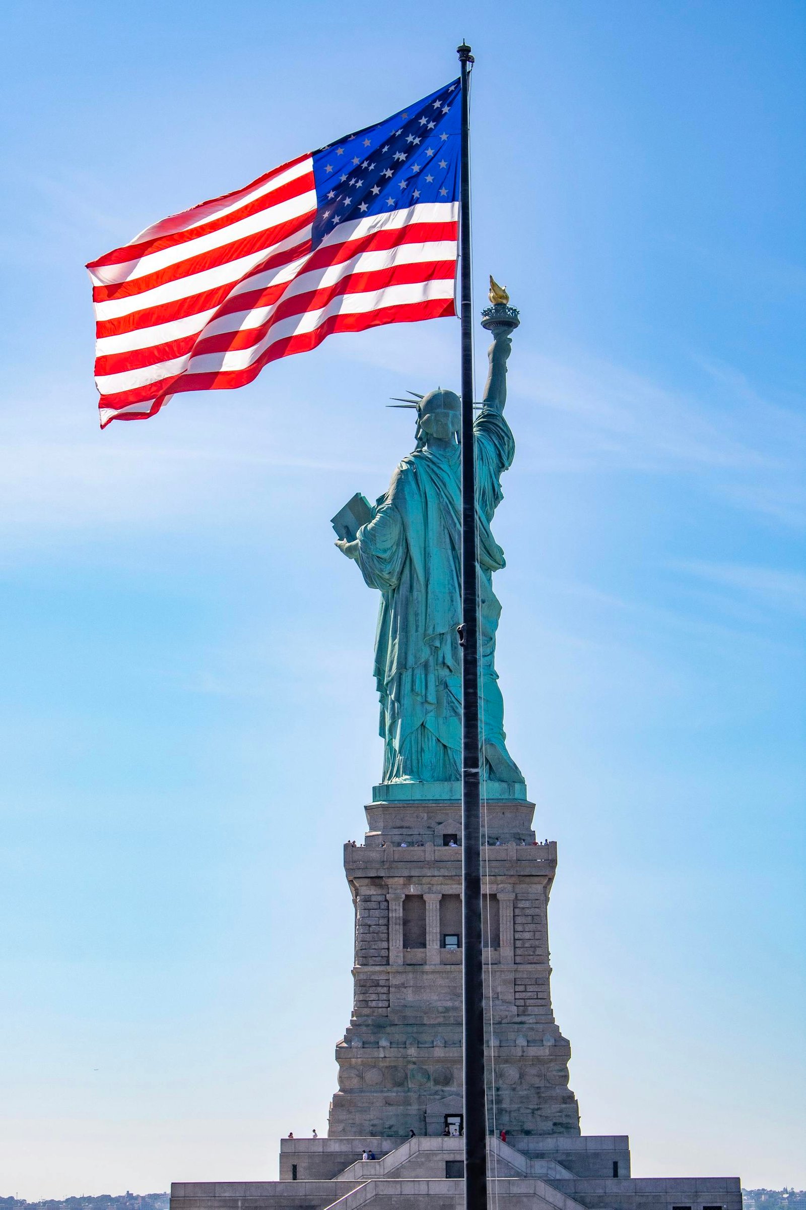 Iconic view of the Statue of Liberty with American flag, symbolizing freedom in New York City.