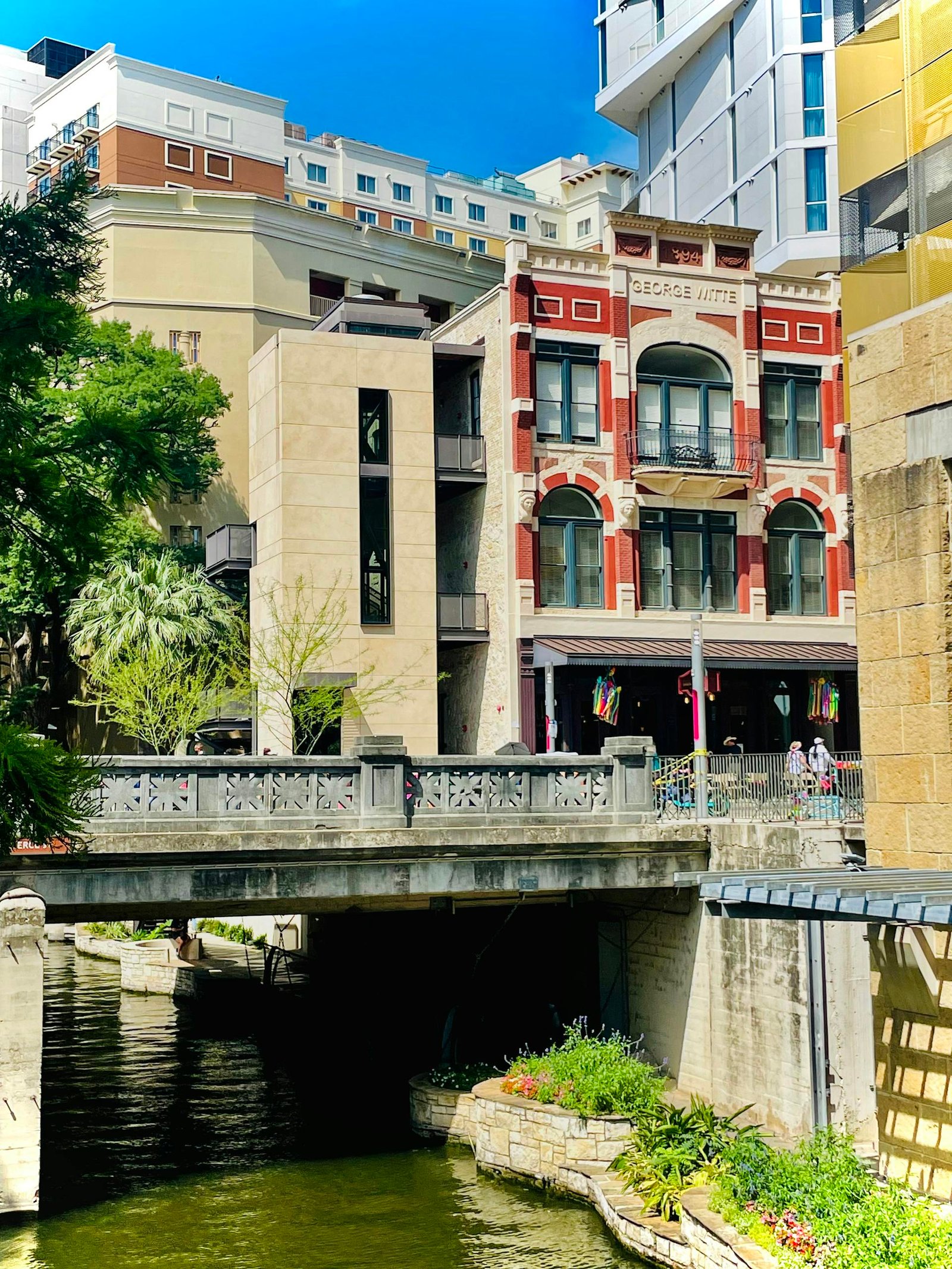 Scenic view of San Antonio's Riverwalk with historic architecture and lush greenery.