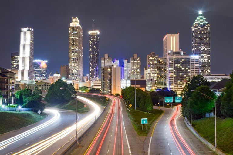 Vibrant night view of Atlanta city skyline with light trails highlighting urban motion.